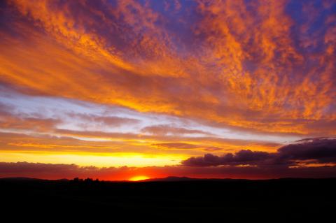 Vibrant sunset over Kendrick, Idaho, with orange and purple clouds above a dark horizon.