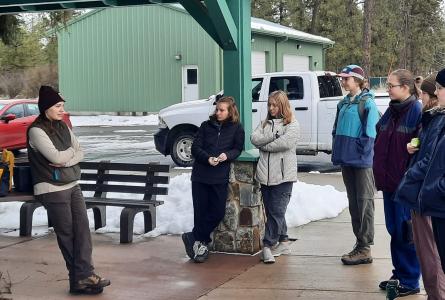 A biologist speaks with university students outside before a field assignment.